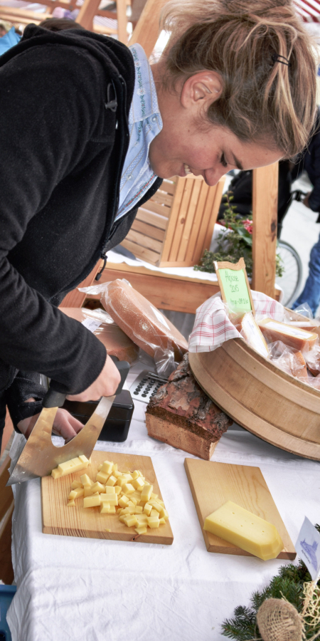 Junge Bäuerin rüstet Alpkäse für die Verkostung. 