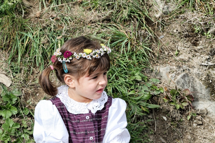 Mädchen ruht sich am Wegrand aus. (© Kellermedia, Grüsch) Blumengeschmücktes Mädchen ruht sich am Wegrand aus