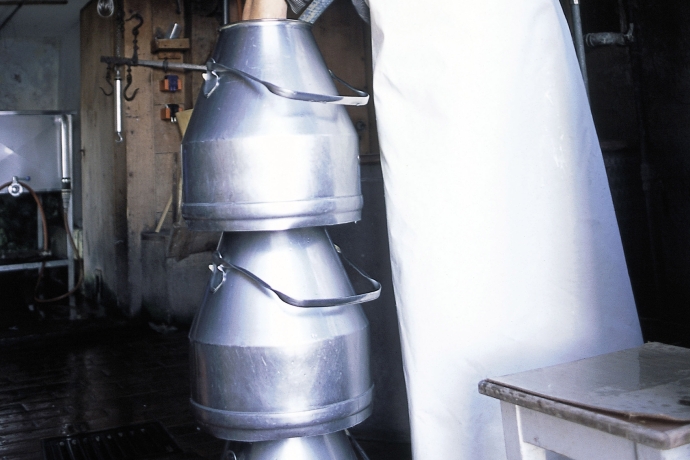 Aufeinander gestapelte Milchkessel werden von Hand vorgewaschen