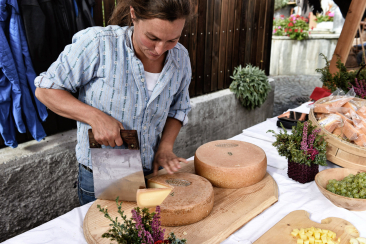 Bäuerin schneidet Alpkäse am Markt vom Alp Spektakel
